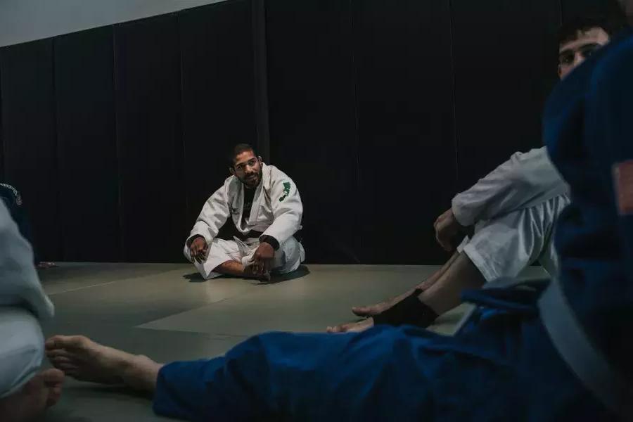 Romulo Melo sitting on the mat with other fighters.