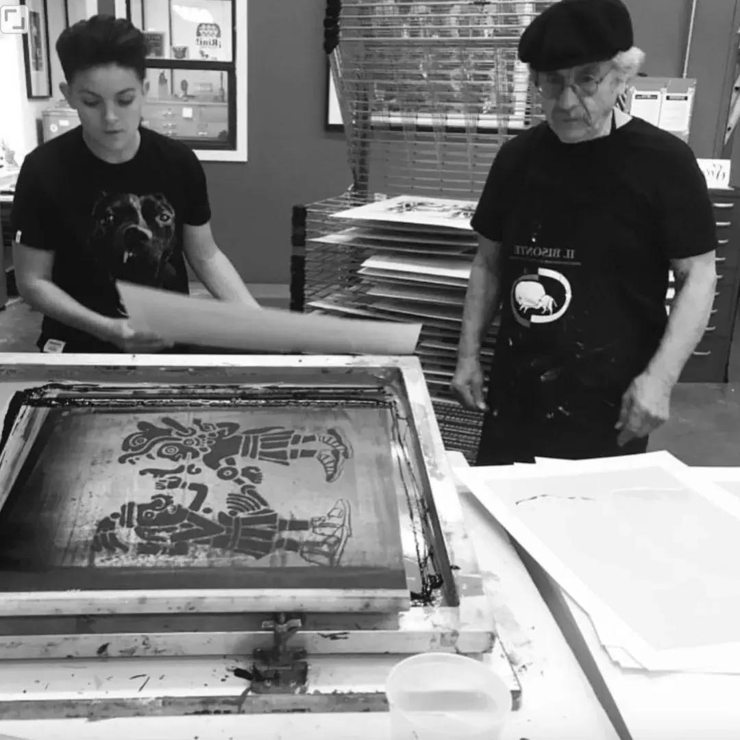 Image of older man and child working on a screen print in black and white