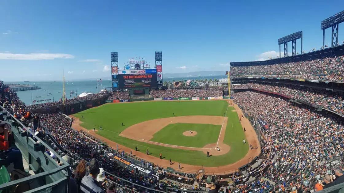 A view of San Francisco's Oracle Park looking out from the stands, with the baseball diamond in the foreground and San Francisco Bay in the background.