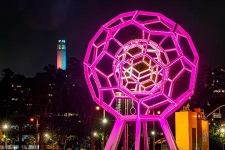 Buckyball shines outside the Exploratorium, with Coit Tower in the background